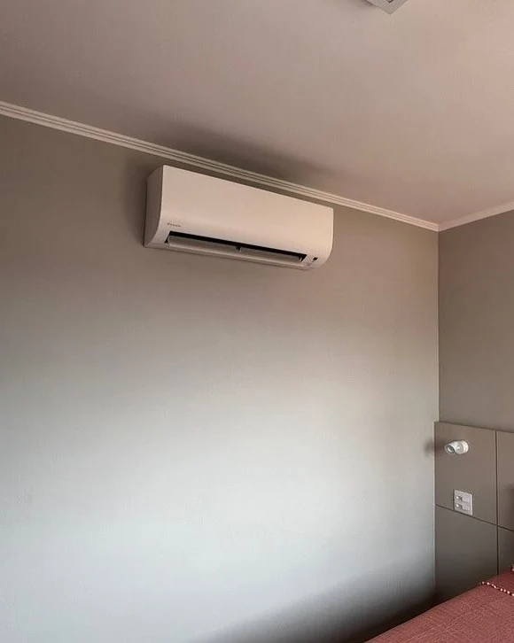 Evaporadora de ar condicionado instalada na parede de um quarto, com a parede fechada e sem canaleta aparente